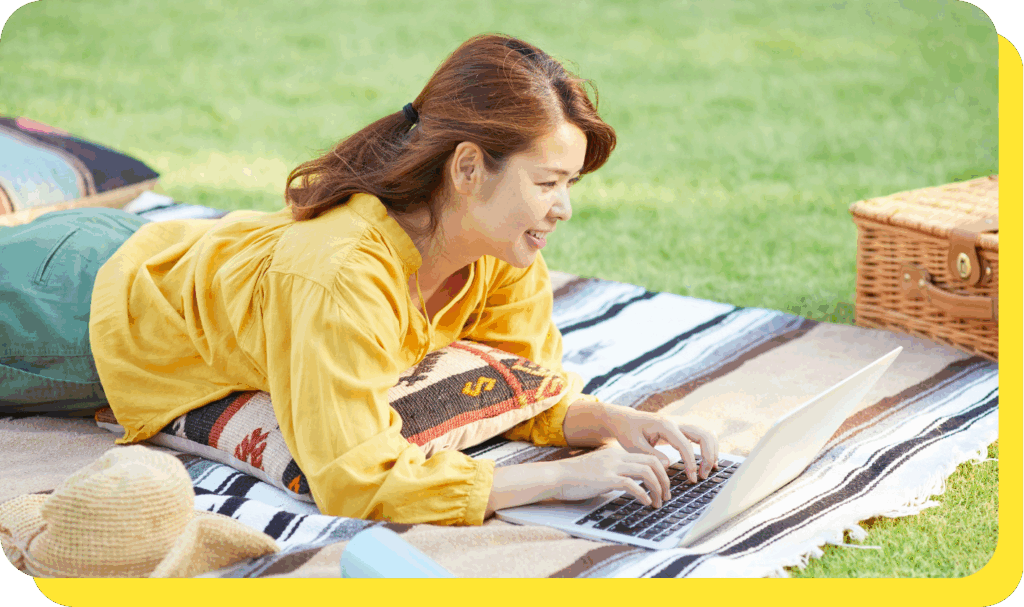 Woman smiling while using a laptop, planning her finances with a goal savings calculator.