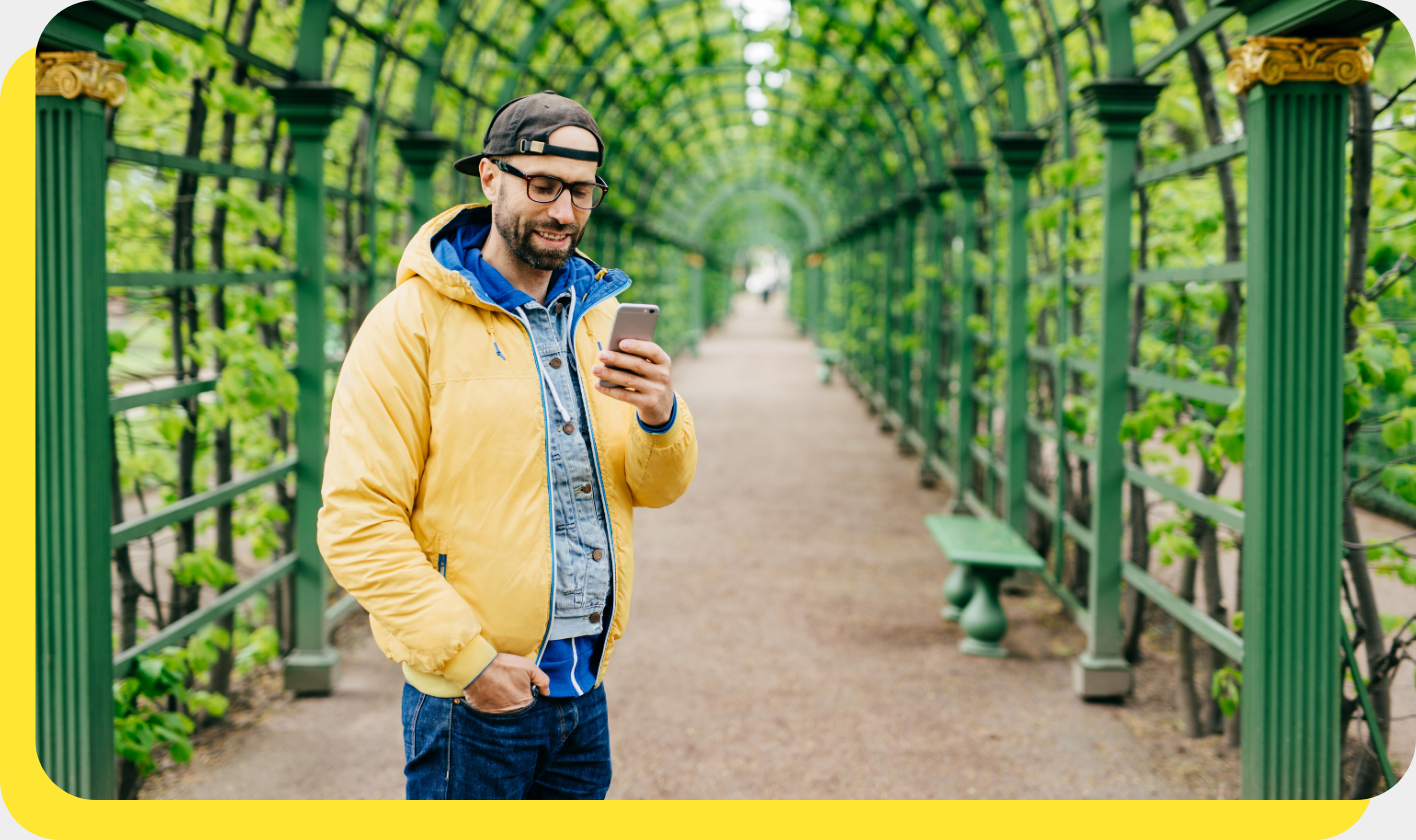Man smiling while using his phone, managing his payroll savings with ease.