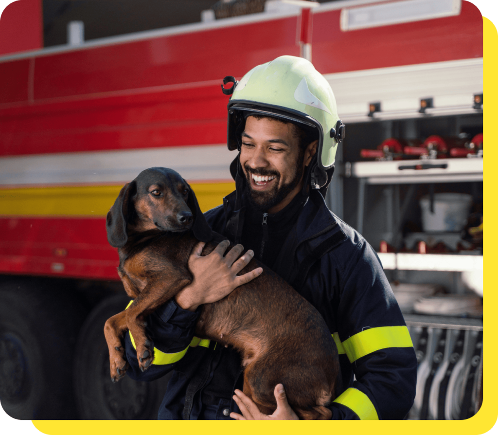 Smiling firefighter in uniform holding a rescue dog, showcasing community service and care.