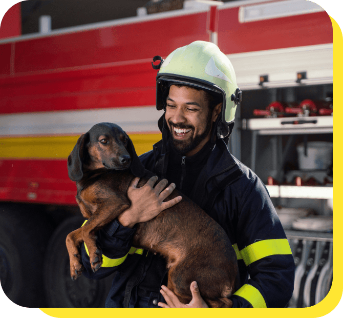 Smiling firefighter in uniform holding a rescue dog, showcasing community service and care.
