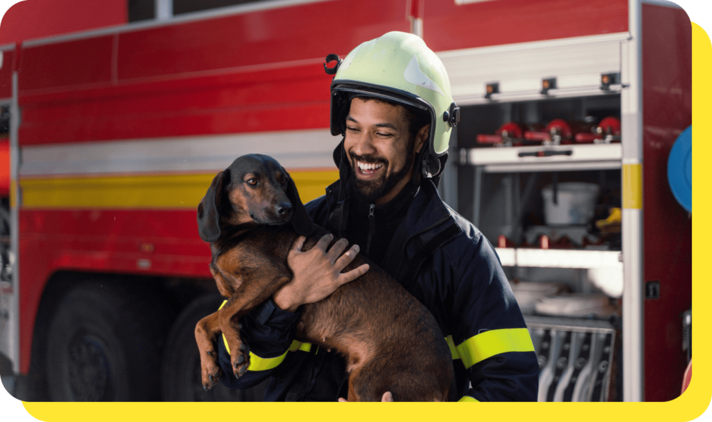Smiling firefighter in uniform holding a rescue dog, showcasing community service and care.