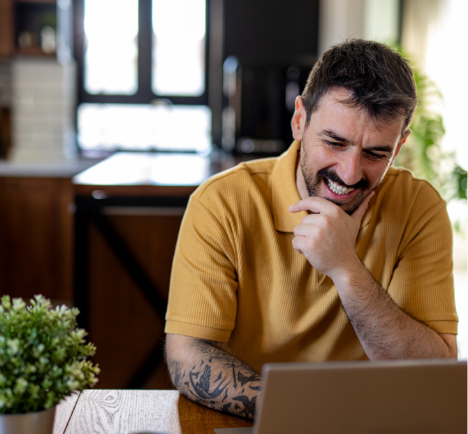 A man smiling while using a laptop, representing ease and convenience of applying for payroll loans online.