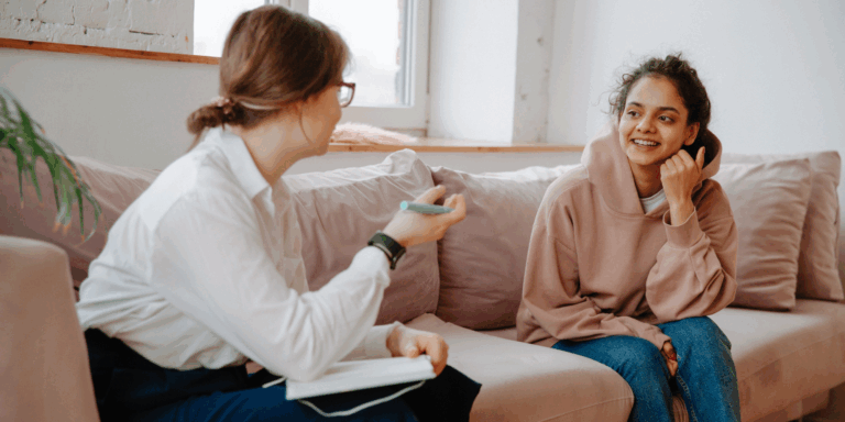 Young person sat on sofa smiling while speaking with debt advisor