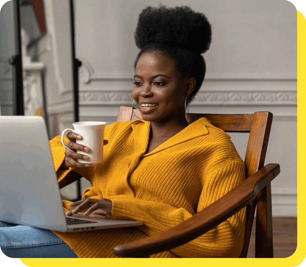 Woman smiling warmly whilst holding a coffee mug and reading about Serve and Protect Credit Union on her laptop, discovering how payroll deduction can help manage her finances effortlessly.
