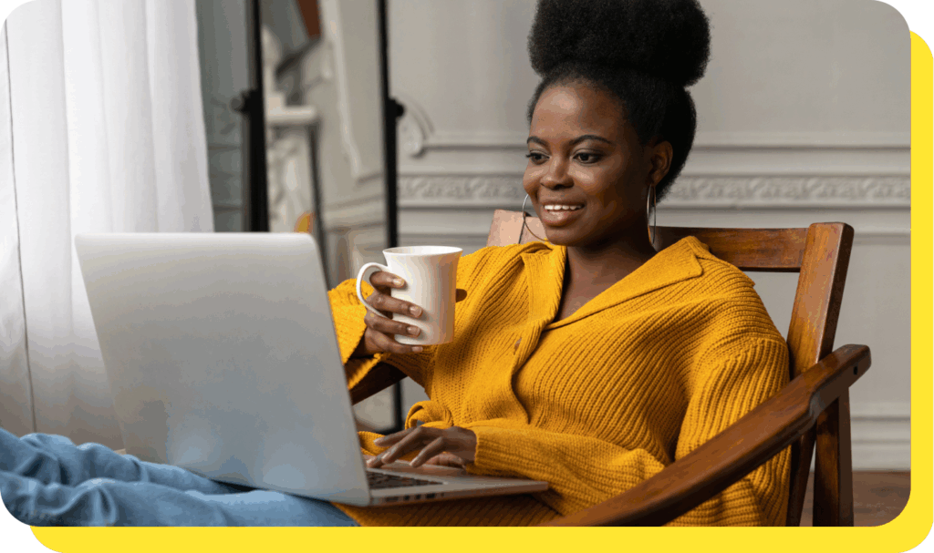 Woman smiling warmly whilst holding a coffee mug and reading about Serve and Protect Credit Union on her laptop, discovering how payroll deduction can help manage her finances effortlessly.