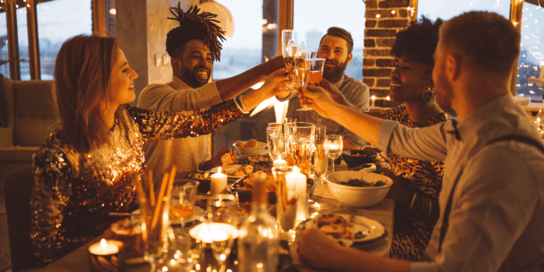 Five people around a table celebrating Christmas after following a simple Christmas budget.