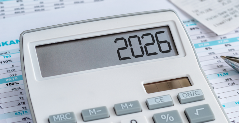 A calculator displaying 2026 with a money saving plan in the background